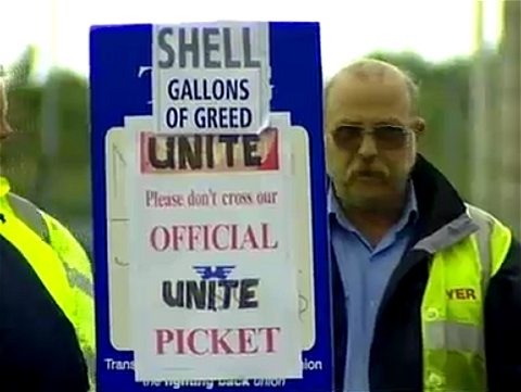 ピケットラインを形成するトラック運転手とプラカード。「SHELL GALLONS OF GREED(シェルはガソリン高騰に乗じた欲張りだ)」との文字が見える。