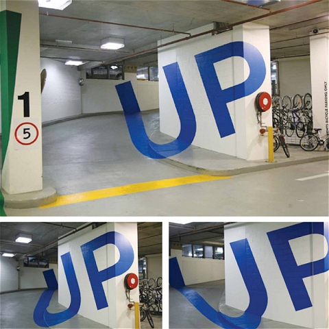 地下駐車場における「UP」(登り)を示す「歪み絵」。入口近くから見ると、「UP」の文字がキレイに浮かび上がって見える。