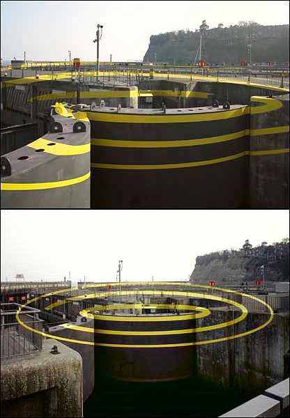 普通に見ると、警戒用のものだろうか、黄色の線が無造作に塗っているだけのように見えるが、ある視点から見るといくつにも重なった同心円が浮き出て見える