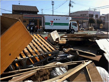 ↑ 未だ復旧が進まず破損した家屋の跡が残る周辺地域と、休業中の店舗、そして移動販売車