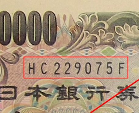 ↑ 現行一万円札の記号と番号。黒色だが、7月19日以降の発行分は褐色になる