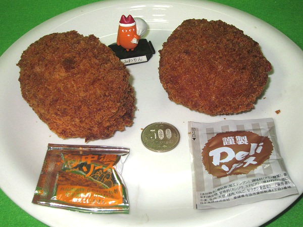↑ ゲンコツコロッケ(左)とゲンコツメンチ(右)。中央部分においたサイズ比較用の500円玉で、その大きさは分かるはず